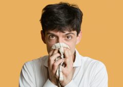 Portrait of a young man blowing nose over colored background